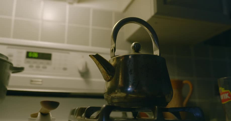 Kettle sits on high gas burner on stove top and reflects light