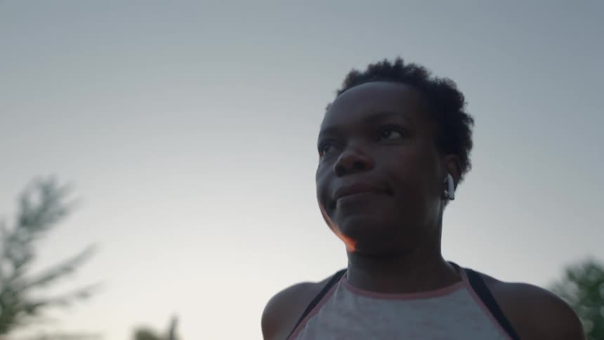 A woman stretches her body preparing for a jog in an empty park at sunset
