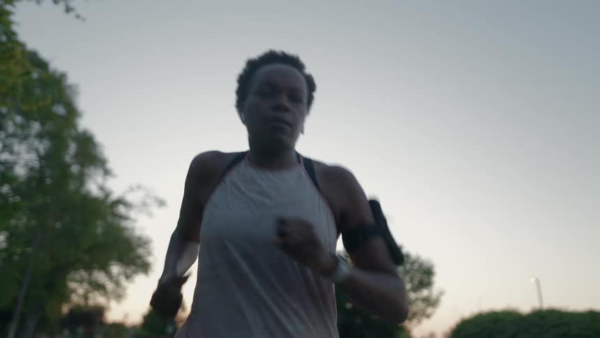 A woman runs down a suburban street with a smartphone attached to her arm