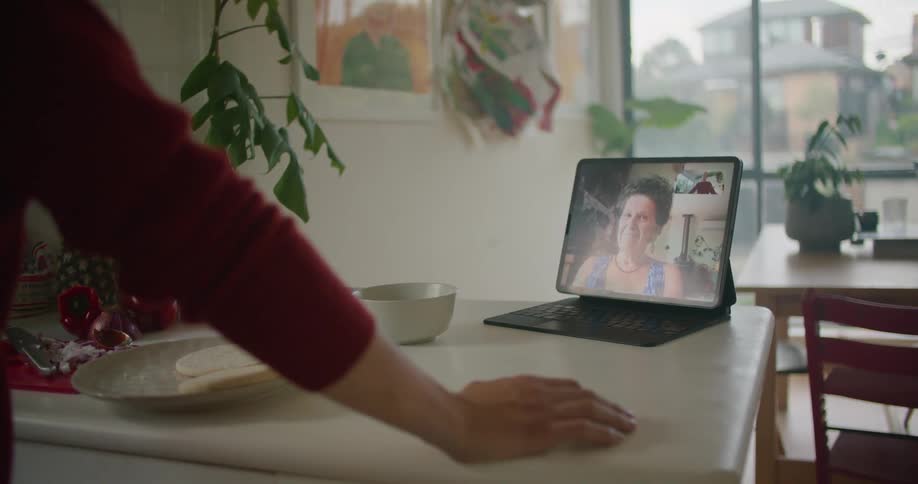 Man eating breakfast talking to a woman on a video call through a laptop