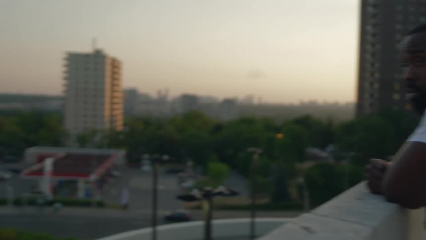 Man standing on the roof of a parking garage in the city at sunset looking at police cars parked on the street