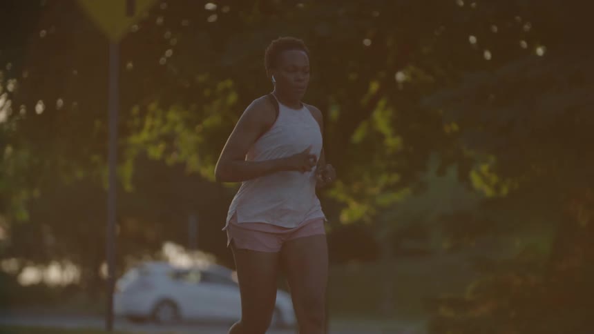 A woman running down a street at dusk