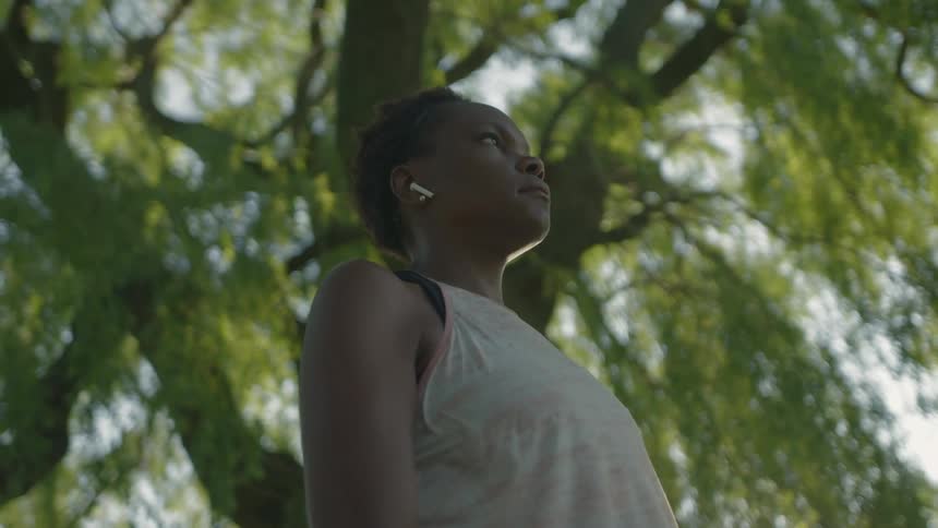 A woman is listening to earbuds and looking around