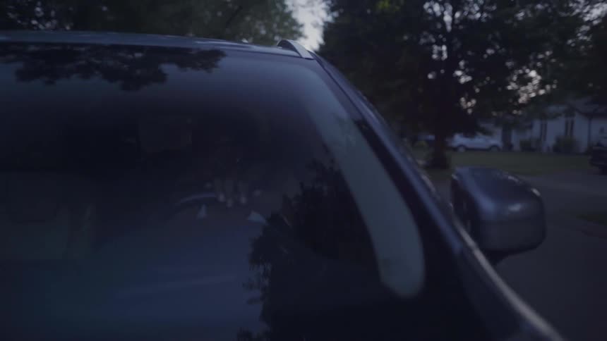 A woman drives a vehicle through a residential area in the evening