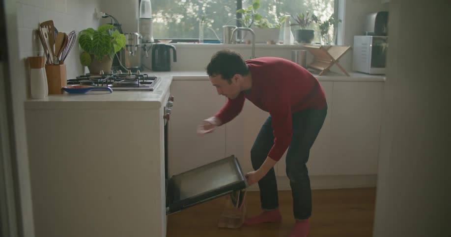A man putting baked goods into the oven