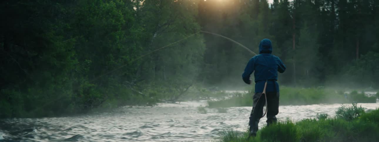 A man walks through a river as he fishes