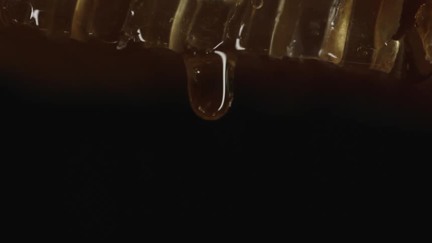 Light reflects off a drop of honey as it falls