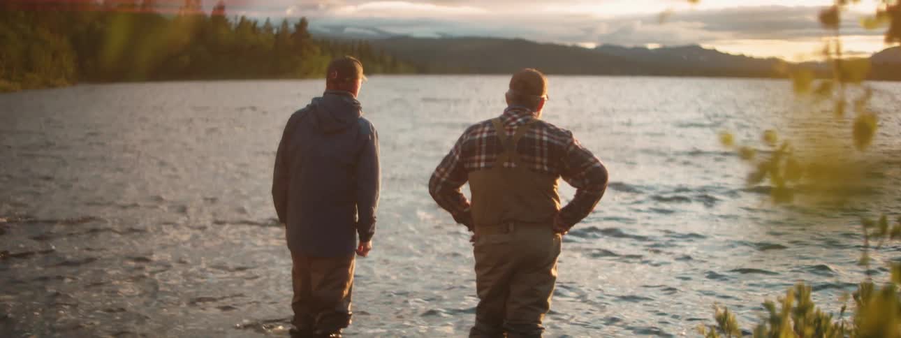 A father and son stand in a lake and talk before wading further in