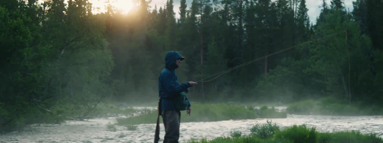A man stands in a river and fishes