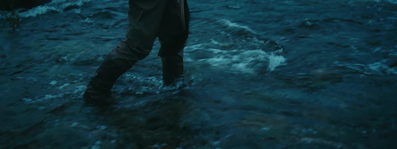 A man is wading through the water to start fishing