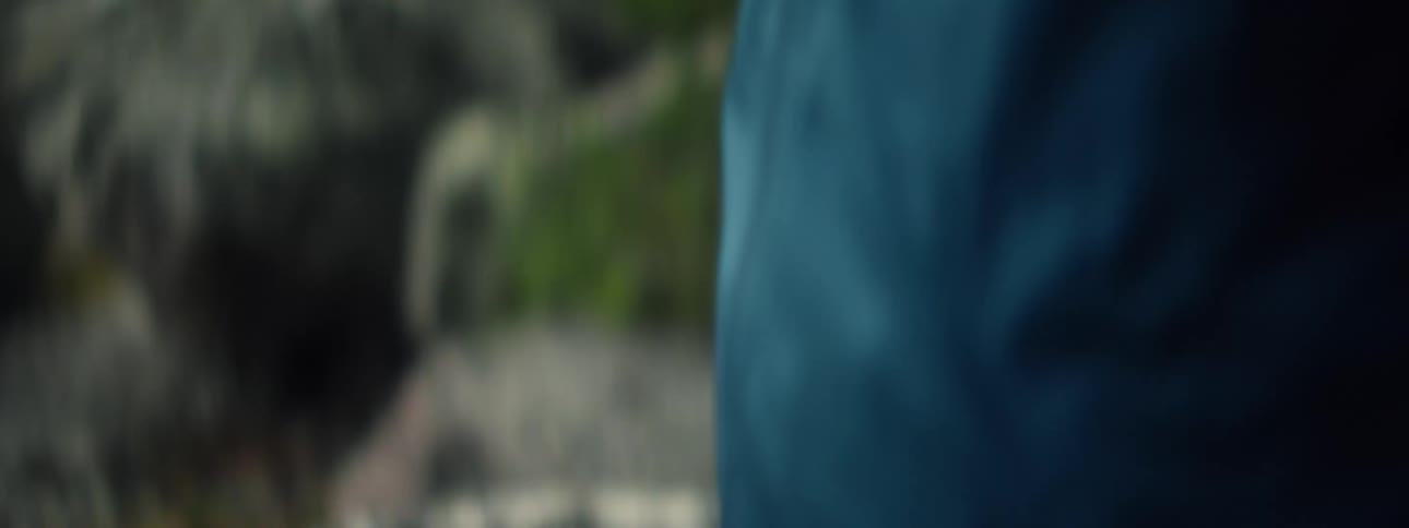 Man wearing a hat with sunglasses and a face mask standing in the forest with a fishing rod