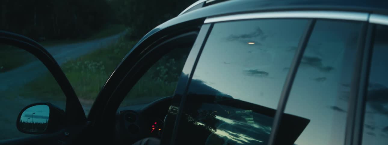 Elderly man boarding a parked car on the drivers side at morning