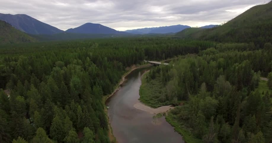 Aerial view of a canal between two forests with a bridge in the distance