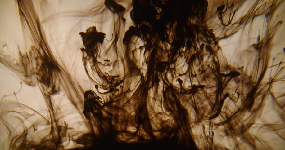 Clouds and ribbons of brown dye rise and float in liquid