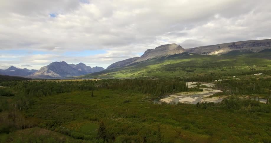 An aerial view of a very green valley with mountains in the distance