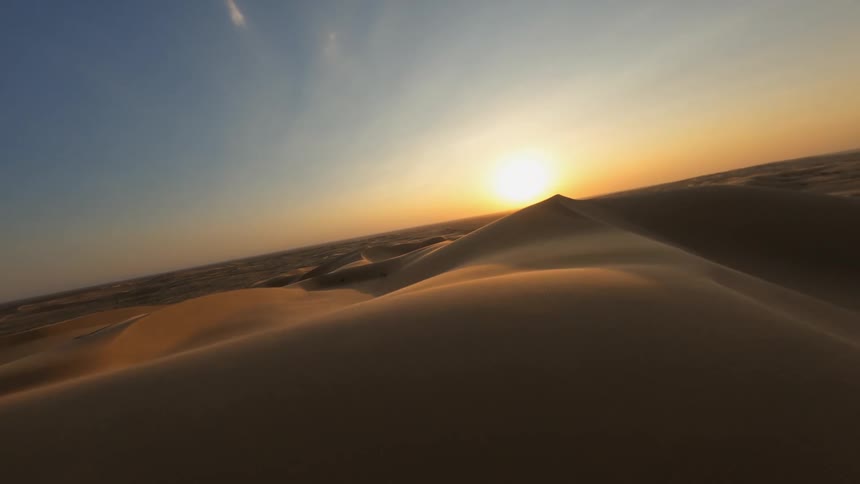 A desert with sand and dunes with the sky and clouds in the background