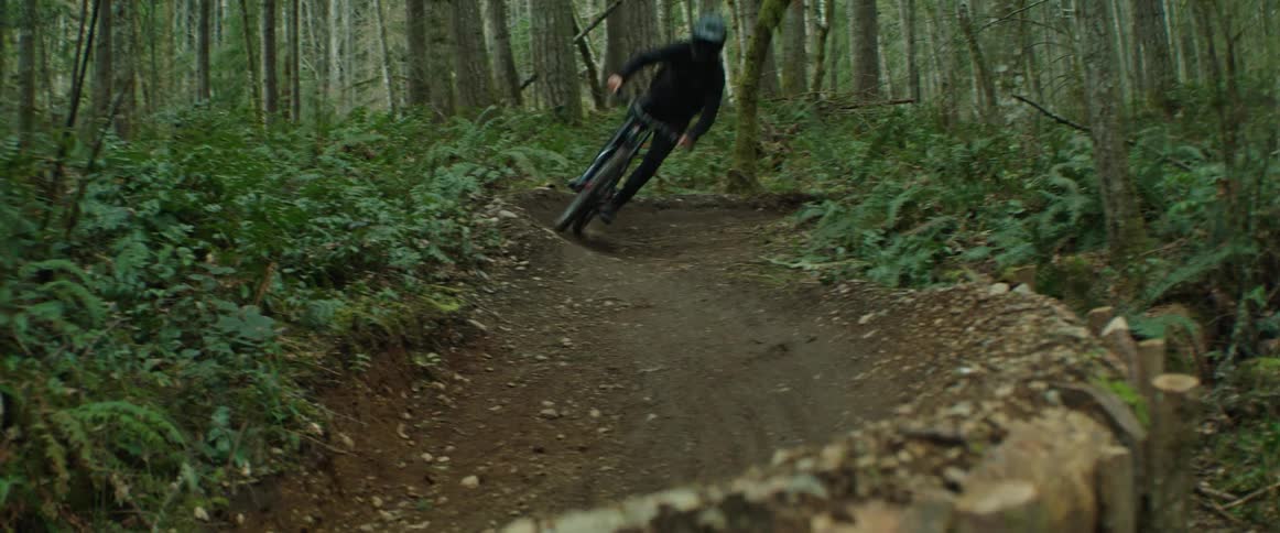 A person with a helmet rides a bicycle through fast trail corners