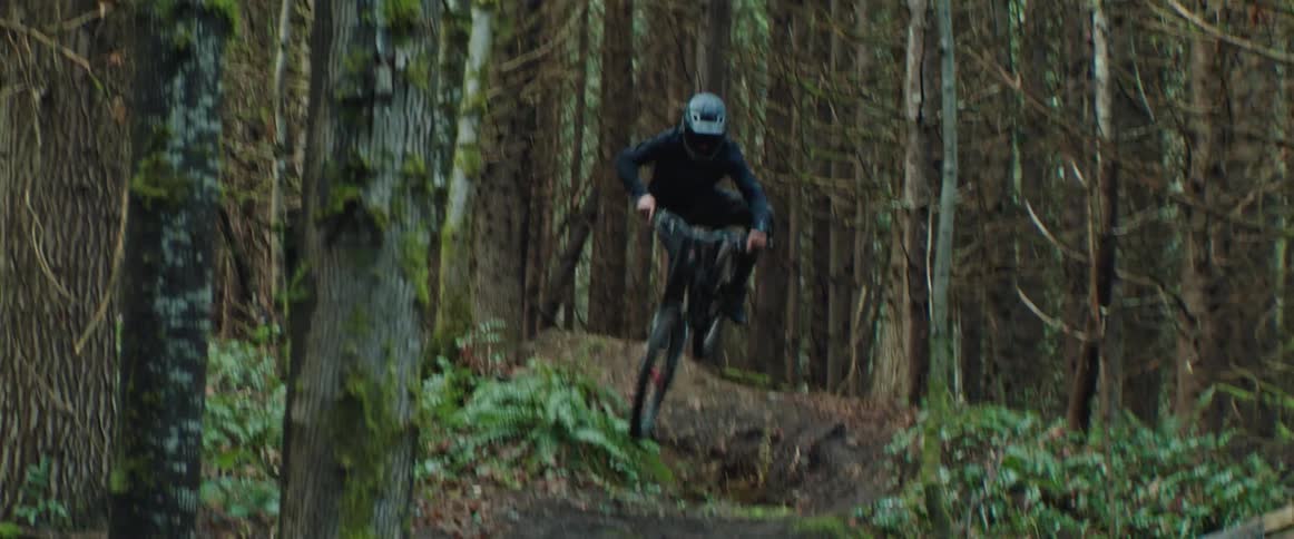 A man jumps his mountain bike while riding a trail in the woods