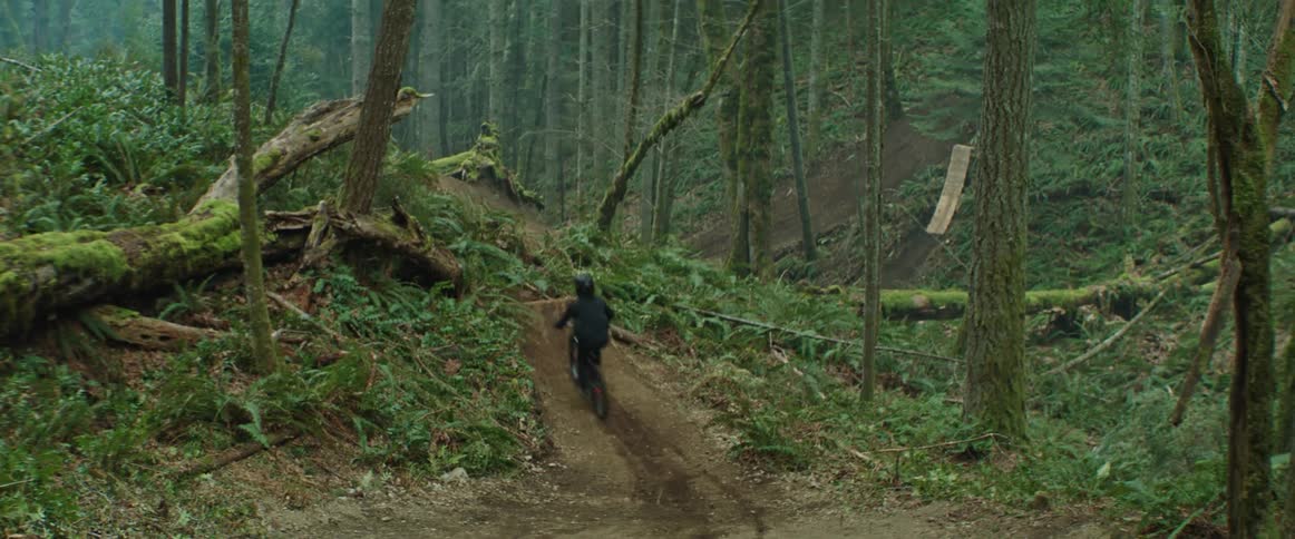 A bike rider jumps into a dirt trail feature