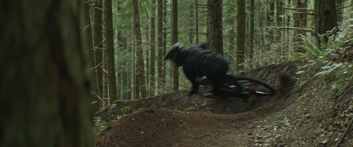 A man carves his mountain bike back and forth through sweeping dirt corners