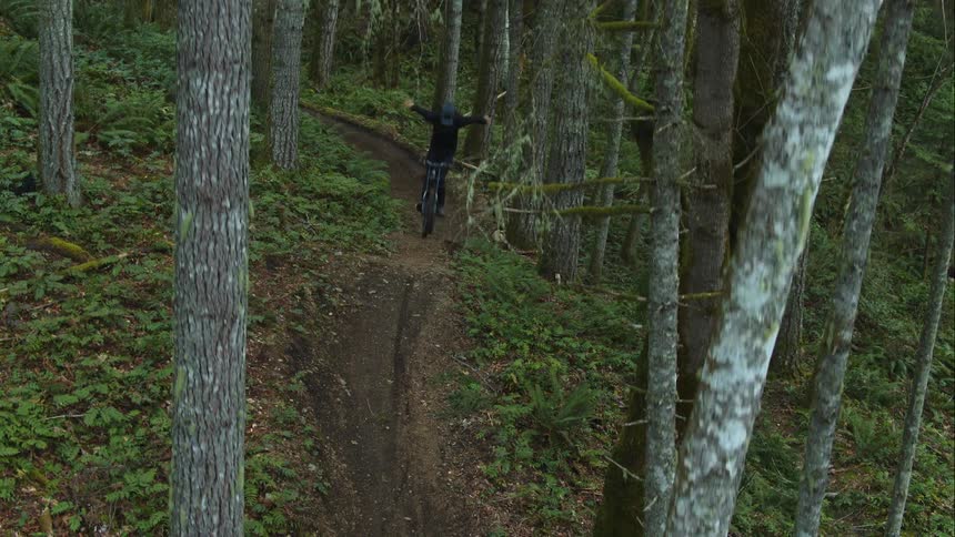 A bike trail rider hits jump and does a no-hander trick