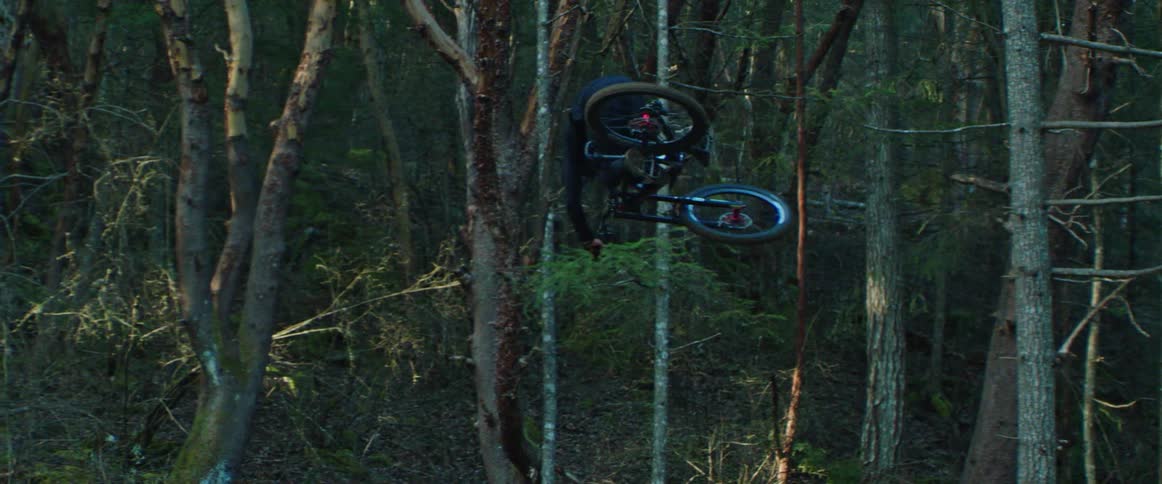 A bike rider hits a large wooden ramp and performs a 360 tabletop trick in the air