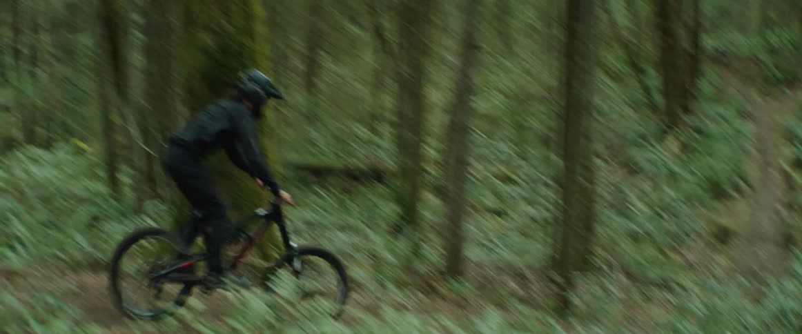 A man on a mountain bike hits a high-speed trail jump and performs a no-hander trick