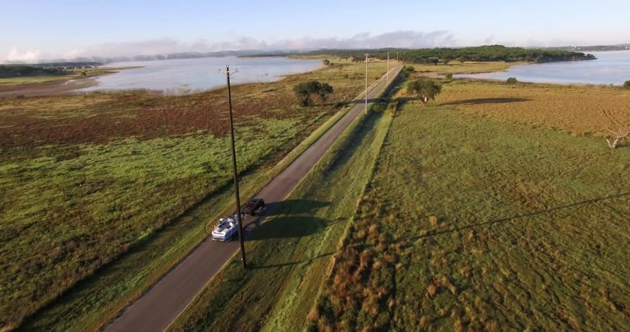 A car drags a boat down a small road