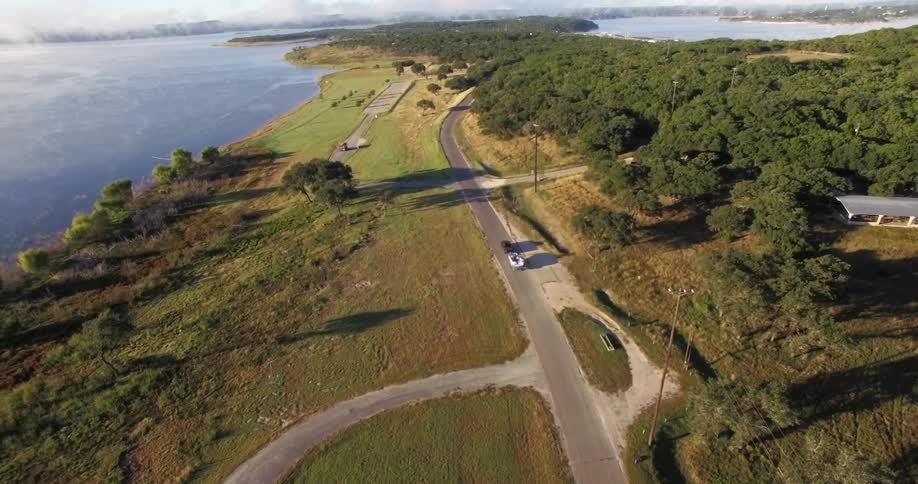 A car driving on a single lane road near the sea
