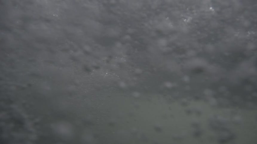 View underwater as bubbles form from a splash above