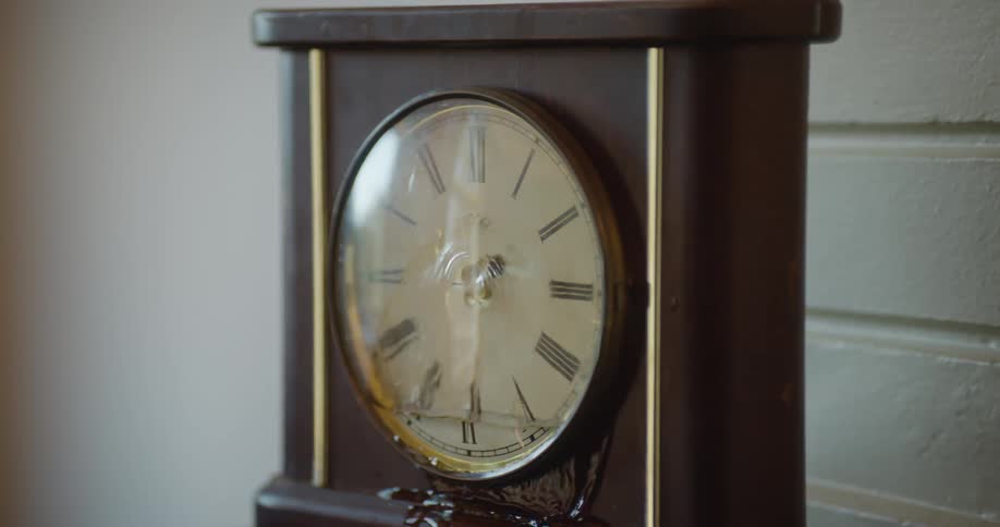 Water flows from center of clock face into space behind glass then flows out onto wood and continuing downward