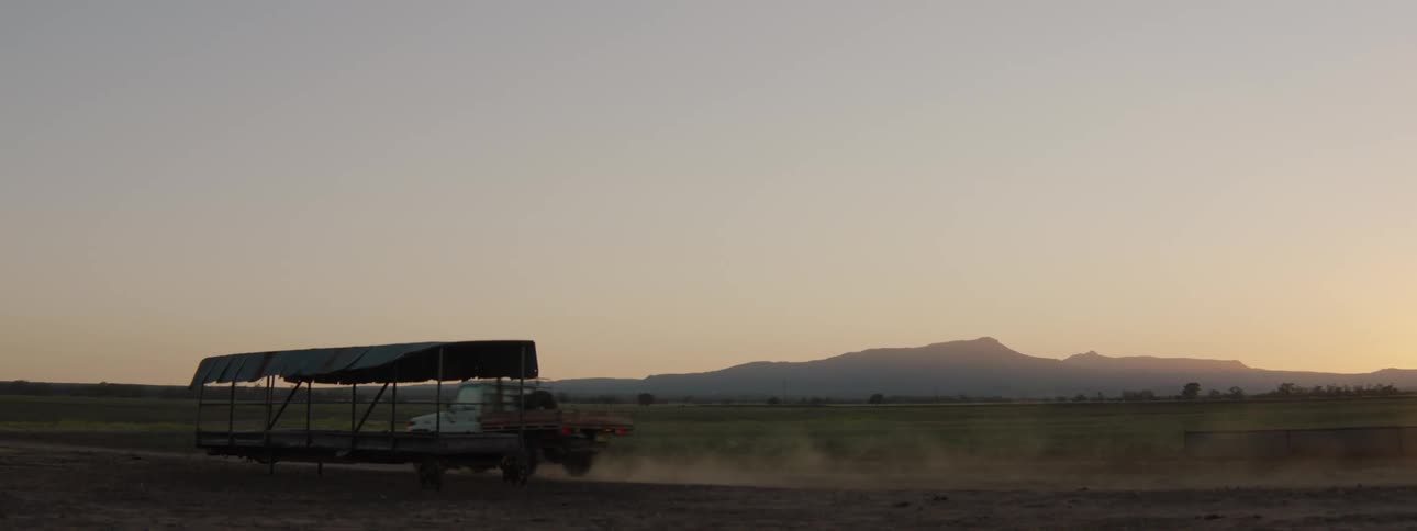 A truck driving in a landscape with a mountain range the sky and clouds in the background