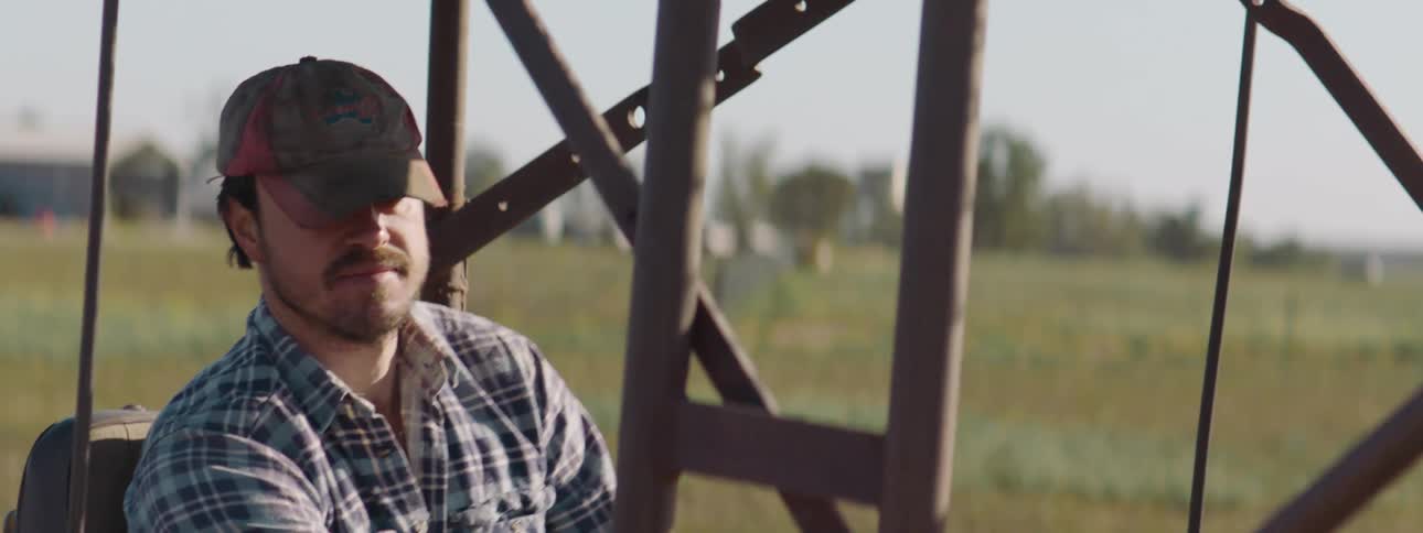 A man is driving a tractor through a farm in spring