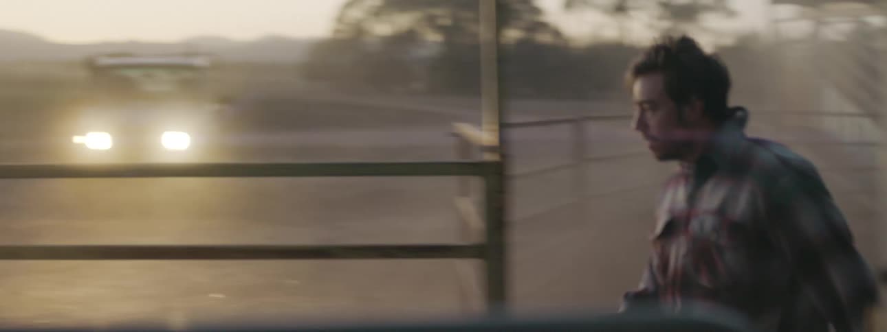 A rancher runs through a corral of cattle and stops to look at heavy dust blowing in