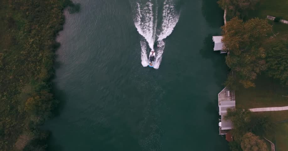 A boat towing a wakeboarder moves up a river