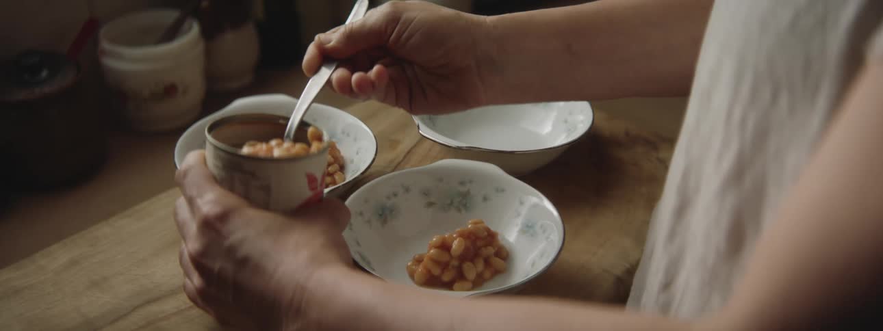 A woman spoons beans into several bowls