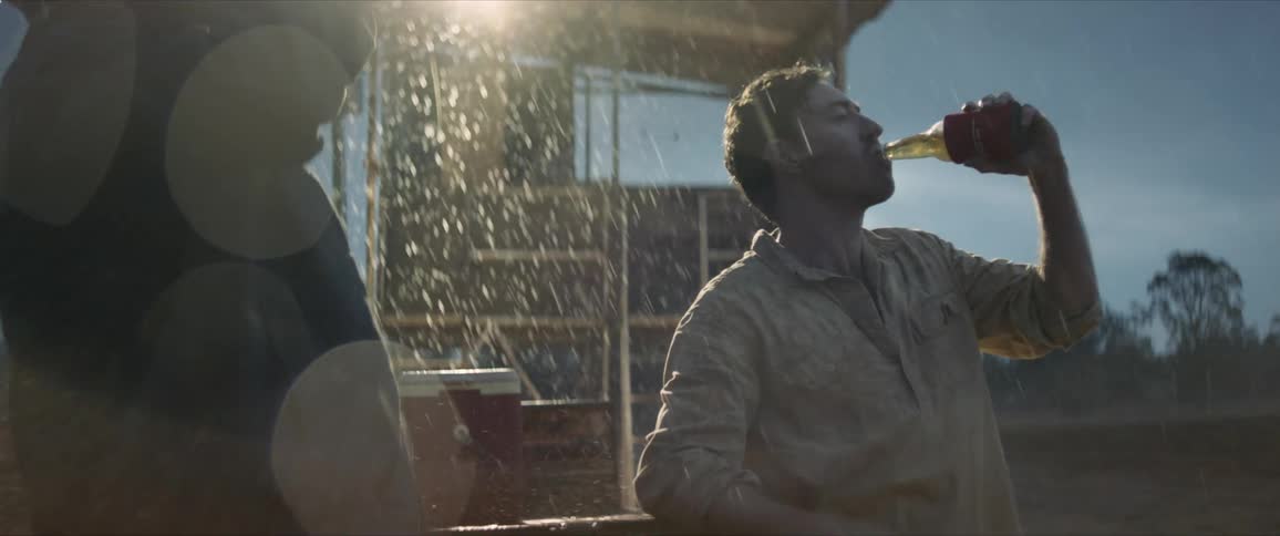Two farmers drink a beer in the rain after the drought