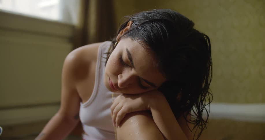 A woman sits in a pool of water with her head resting on her knee