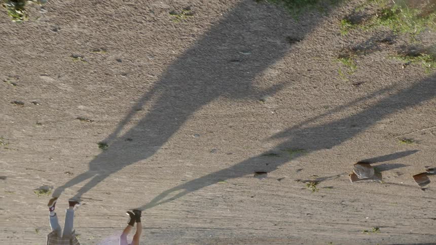 The elongated shadows of two people walking cast on rock