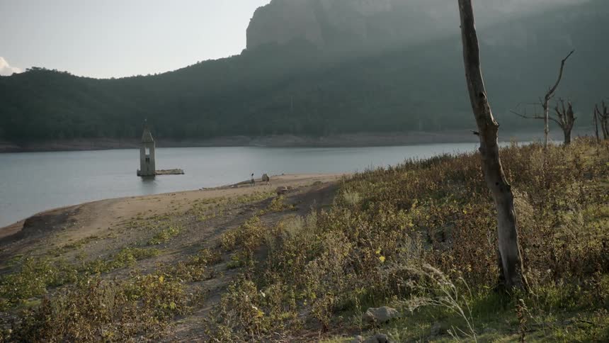 Moving over a shoreline as people stand near the water