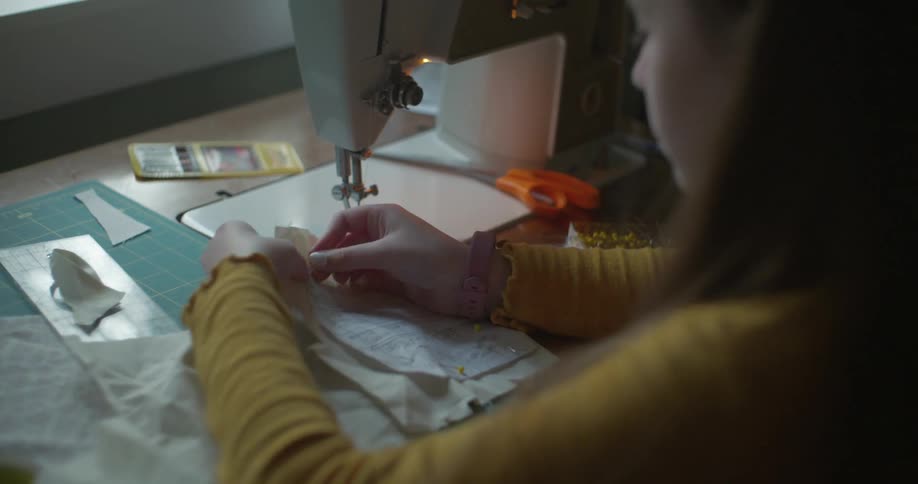 A woman is working at a sewing machine with fabric