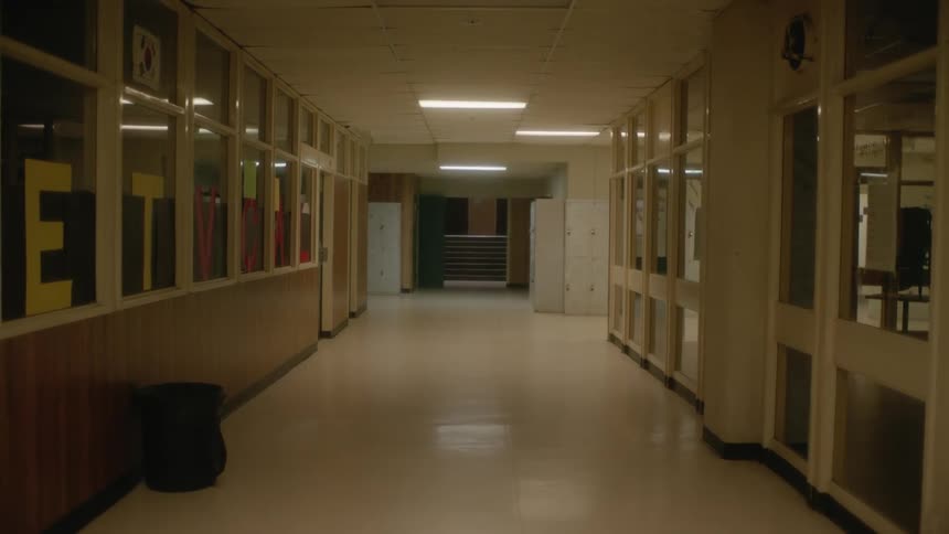 A room with a hallway with a doorway a staircase and a person in the background