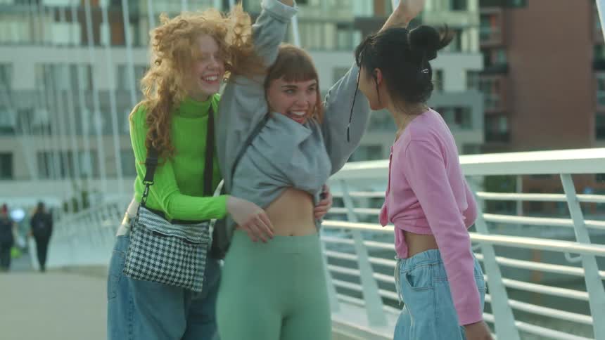 A group of women meets and hugs on a bridge
