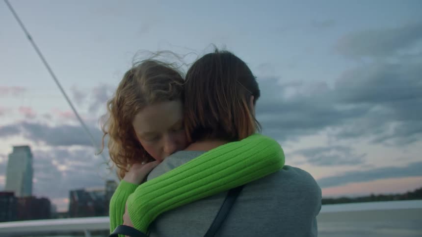 Two women hug near the water