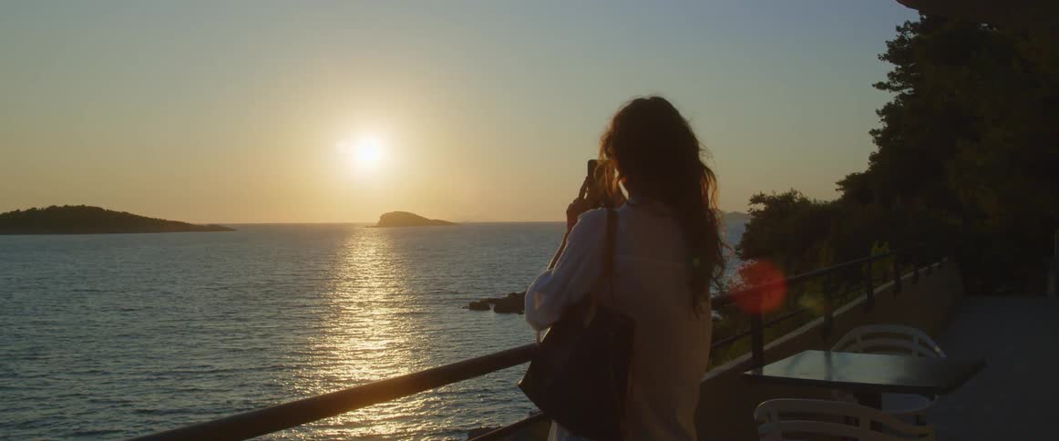 A woman taking a photo of a sunset