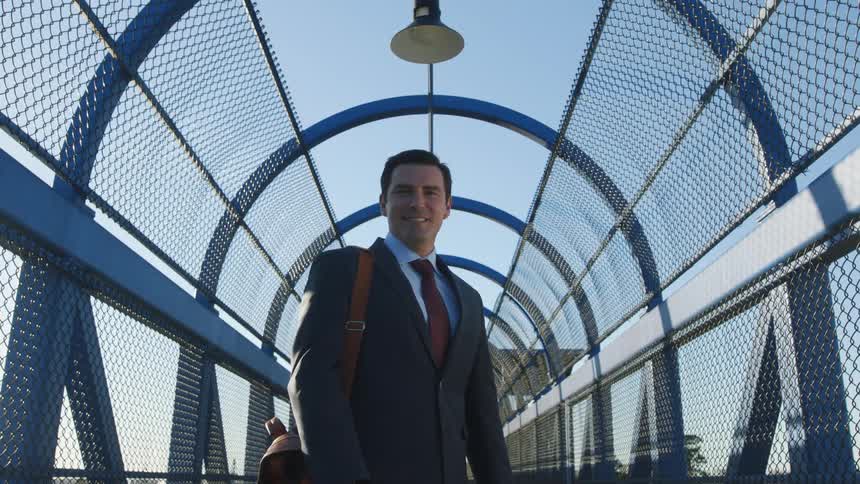 A man in a business suit stands and poses in front of the camera