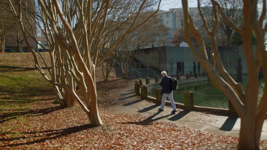 A man walks along a path next to a pond