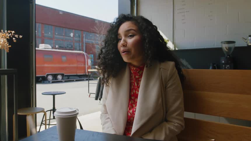 A woman is sitting in a booth in a restaurant talking to another woman