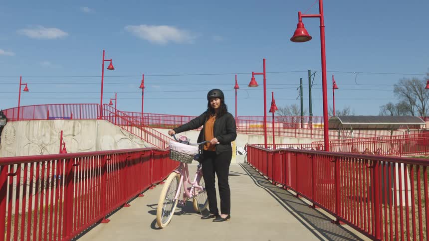 A woman standing and smiling with a bike