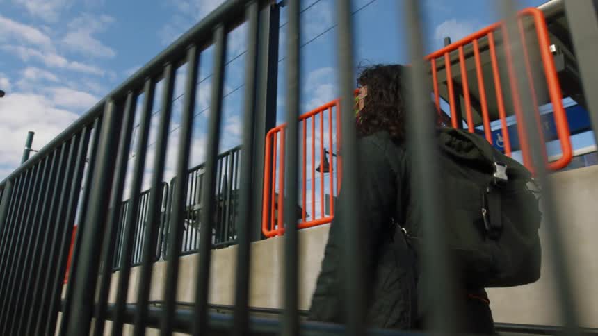 A woman walks past the black fence
